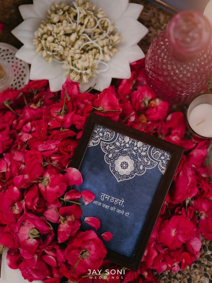 A beautiful detail from the Mehfil-e-Mehendi, with a framed quote nestled in a bed of red rose petals.