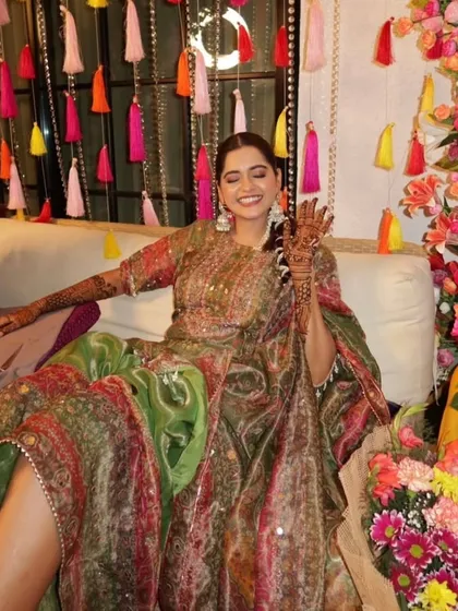 A happy bride showing off her henna against the colorful tassel backdrop I created. My goal is to design spaces that are not just beautiful but also perfect for capturing joyful memories.