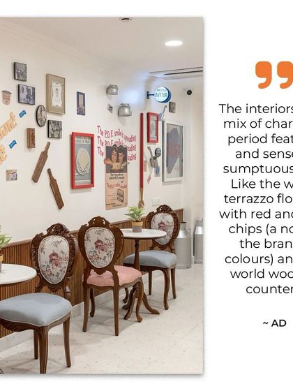 This quote from Architectural Digest highlights the design intent: to mix charming period features with a sense of modern sumptuousness. The image shows the seating area, where old-world wooden counters meet terrazzo flooring that subtly incorporates the brand's colors.