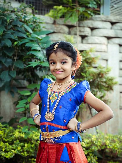 This young girl is dressed in a beautiful South Indian traditional outfit, posing with confidence. We offer outdoor shoots for traditional portraits to capture them in natural light.