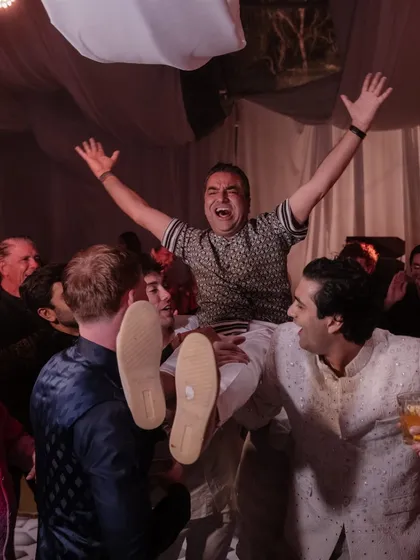 The bride's father gets hoisted up by friends at the afterparty. It’s a moment of pure, uninhibited joy, showing that wedding celebrations are for every generation to let loose and have fun.