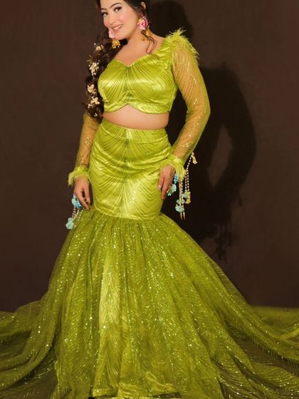 A full view of the modern lime green fish-cut lehenga, perfect for a Mehendi or cocktail night. The look is accessorized with floral kaleeras and earrings for a touch of tradition.