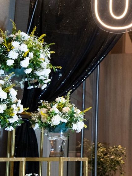Step into the grandeur of a 50th birthday extravaganza. The entrance was designed to be dramatic and elegant, with beautiful white floral arrangements set against a sparkling black backdrop to welcome guests to the surprise party.