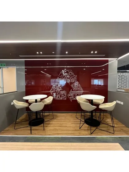 A breakout nook featuring two high-top tables against a bold red glass wall with custom graphics. This space provides an alternative work point for employees, promoting a dynamic and flexible office culture.