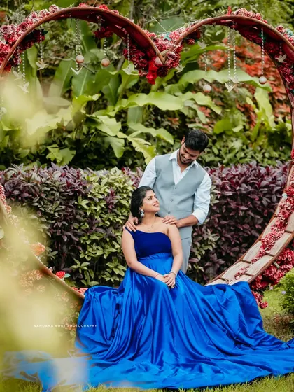 A romantic portrait of a couple framed by a large heart-shaped floral installation in a garden. This image captures the love and anticipation of their journey together.