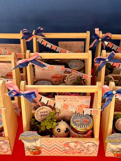 These budget-friendly baby shower hampers feature a cute elephant theme. Each pinewood basket contains a resin planter with a jade plant, a jar of handmade chocolates, and a personalized thank you card.