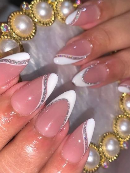 A modern abstract French manicure with a sheer base and swooping white tips lined with silver glitter.