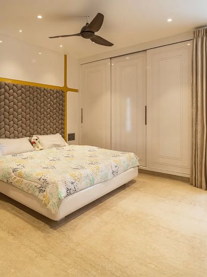 A wider view of the master bedroom, showing the spacious layout and the ample natural light from the large window.