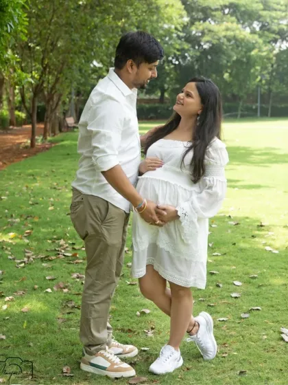 A beautiful portrait of the couple standing together in the park. The natural light and green surroundings create a fresh and vibrant feel.