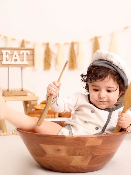 A playful shot of the baby chef kicking his feet up while sitting in a mixing bowl. This image captures the fun and energy of a toddler during a creative studio session.