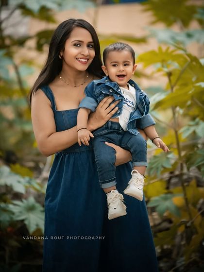 A lovely outdoor portrait of a mother and her baby. Dressed in matching denim against a lush green backdrop, this photo captures a simple, beautiful moment of connection.