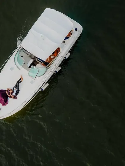 An aerial drone shot of a couple relaxing on a luxury yacht in Goa. This perspective offers a unique view of their exclusive experience, combining romance with a touch of opulence.