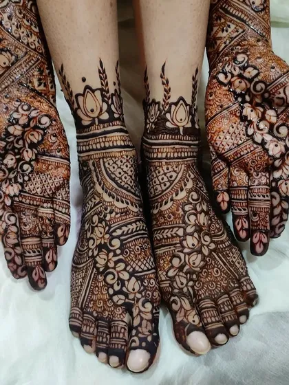 A stunning shot of the coordinated hands and feet for a bride, featuring lotus cutwork and traditional Indian patterns.