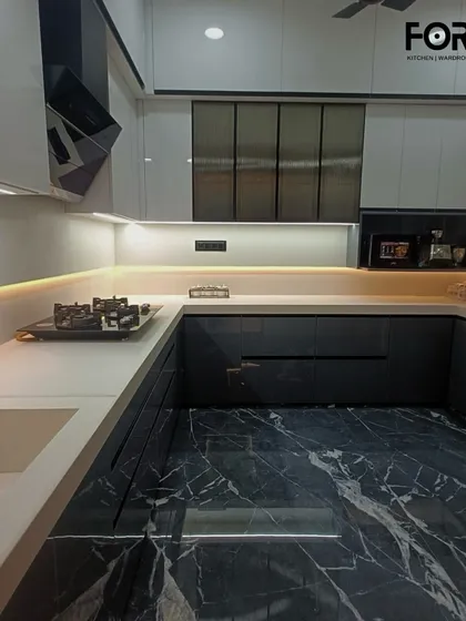 An elegant U-shaped kitchen that combines dark grey base cabinets with white overhead units. The design is defined by its luxurious black marble flooring, handleless profile, and warm under-cabinet lighting, creating a sophisticated and high-contrast look.
