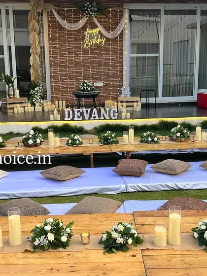We created a cozy outdoor movie night for a 14th birthday. This unique setup includes low wooden tables with floral centerpieces, comfortable floor seating with cushions on the lawn, and a large projector screen for the main event.