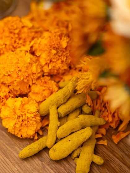 A close-up of raw turmeric roots and marigold flowers. These traditional elements are central to the haldi ceremony and add an authentic touch to the decor.