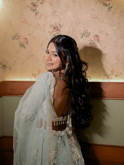 A charming close-up of the bride looking back over her shoulder. This shot highlights her beautiful hair, makeup, and the delicate details of her backless blouse.