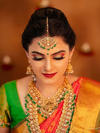 A classic beauty shot focusing on the face, makeup, and jewelry. The lighting is carefully controlled to highlight the shimmer of the gold jewelry and the rich colors of the makeup and saree.