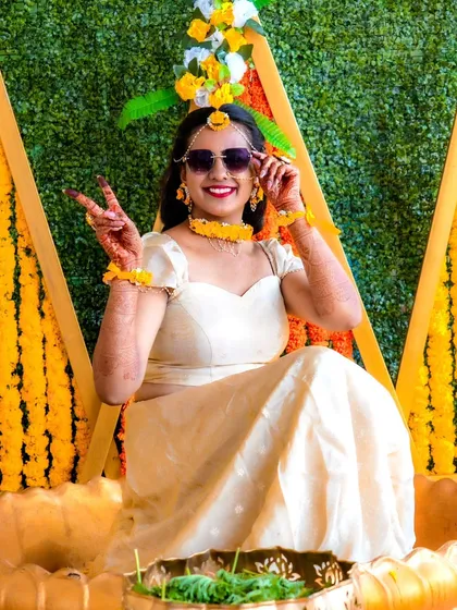 A stylish portrait of the bride at her Haldi ceremony. The vibrant yellow decor and her happy pose perfectly capture the festive spirit of the day.