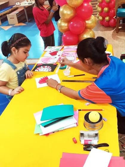 An instructor guides a child through a card-making activity for Mother's Day.