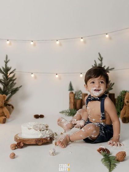 A happy smile from the birthday boy, sitting proudly in his woodland-themed set with his smashed cake.