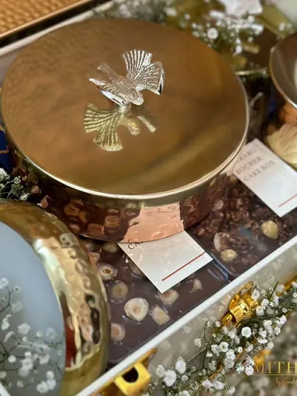 This gender reveal hamper features my signature hammered-gold containers with bird-shaped lids, filled with decadent treats. The mix of blue and gold agate coasters adds a touch of luxury to the celebration.