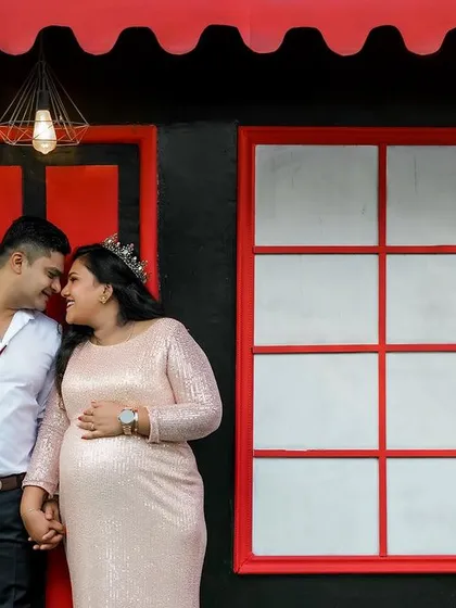 Your love story is at the heart of it all. This shot shows a quiet, intimate moment between an expecting couple, captured against one of the modern, vibrant backdrops at our Bangalore studio.