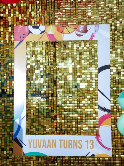 A sports-themed photo frame against a gold sequin wall, ready for guests to take fun pictures.