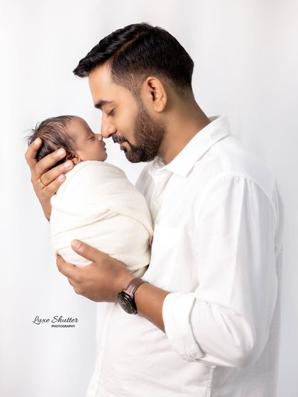 A classic father and son portrait, with the baby swaddled cozily in his father's arms.