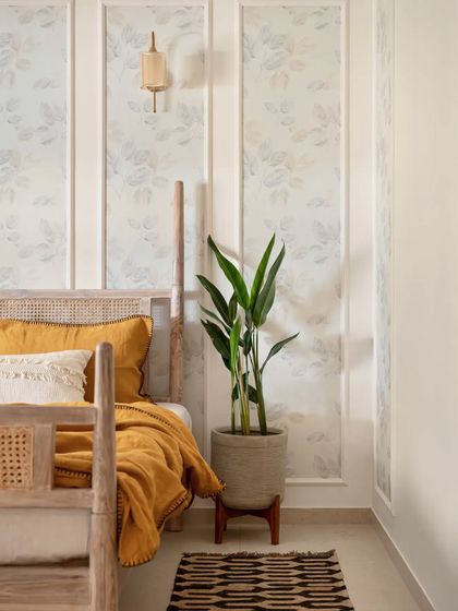 For this guest bedroom, I used an off-white color palette to create a light and airy atmosphere. The four-poster bed with a cane headboard is the room's centerpiece, while wallpaper within the wall beadings adds a touch of subtle character.
