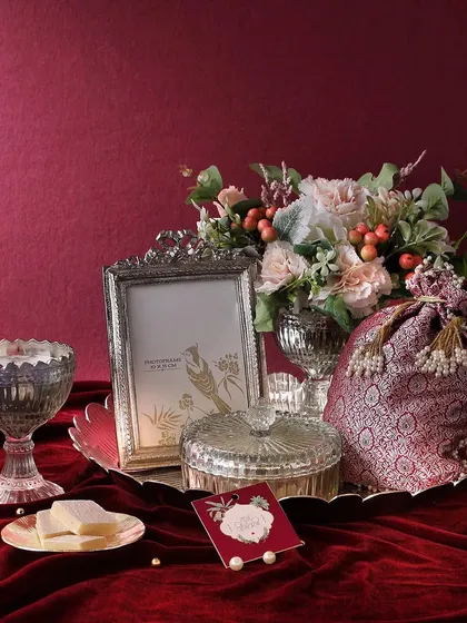 For a touch of royal elegance, the Shimmering Silver hamper is a perfect choice. It combines a silver photo frame, a candle, and a flower arrangement with our mini butter cookies and honey choco almonds.