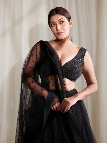 A full-length portrait of a model in an elegant black lehenga with a sheer dupatta, exuding grace and sophistication.