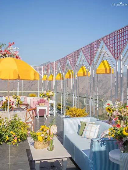 The long line of house-shaped metal structures creates a unique and graphic silhouette against the mountain landscape.