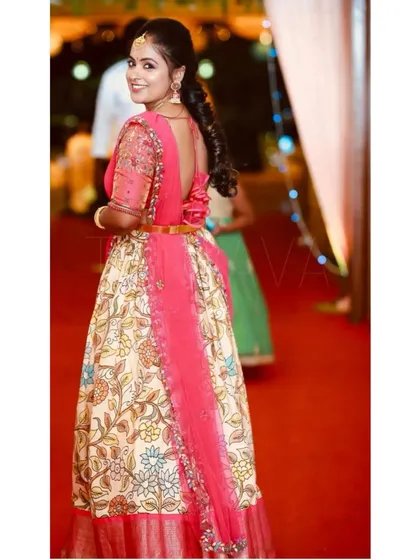 This custom-made half saree was designed for a beautiful client in Australia. It combines a traditional Kalamkari print skirt with a vibrant pink, hand-embroidered blouse and a delicate net dupatta for a complete wedding-ready look.