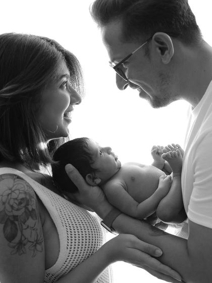 A beautiful black and white portrait of a family. The mother's smile and the father's gentle gaze at the baby create a picture of pure happiness.