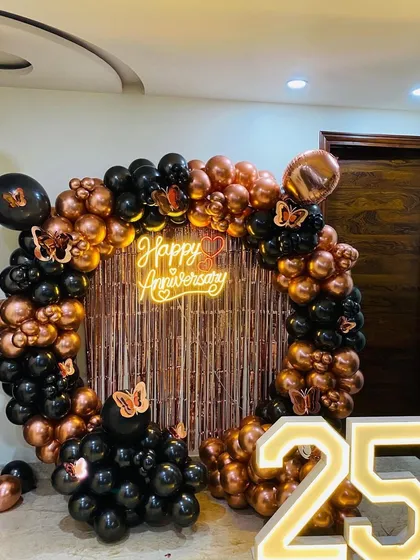 For milestone anniversaries, we design elegant backdrops that celebrate the occasion. This 25th-anniversary setup includes a circular balloon arch in black and rose gold, a custom neon sign, and large, illuminated marquee numbers.