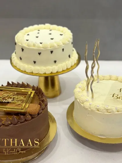 A trio of beautiful birthday cakes. This image shows the versatility of my designs, featuring a chocolate Biscoff cake, a classic white cake with gold candles, and the chic black heart design.