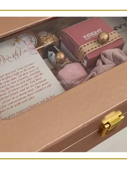 The contents of the wedding gift for a friend, revealed. The rose-gold box contains a personalized letter, makeup, perfume, and chocolates.