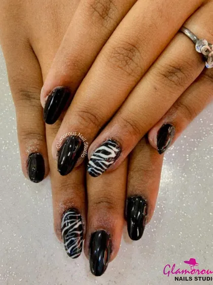 Take a walk on the wild side with this classic black manicure, featuring bold, hand-painted zebra print on the accent nails for a fierce touch.