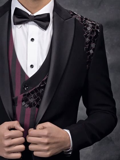 The combination of a classic black suit with subtle, modern embellishments and a pop of color in the waistcoat creates a truly interesting look.