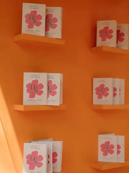 A wall displaying custom-designed welcome booklets for guests, featuring the couple's floral monogram.