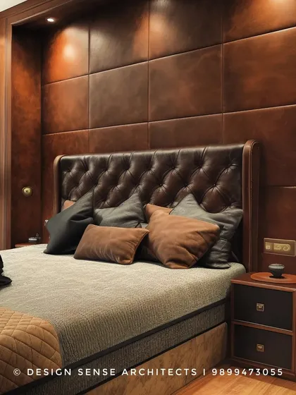 A bedroom that exudes warmth and masculinity, featuring a tufted leather headboard and a full wall of matching leather panels. The dark wood and earthy tones create a cozy, den-like feel.