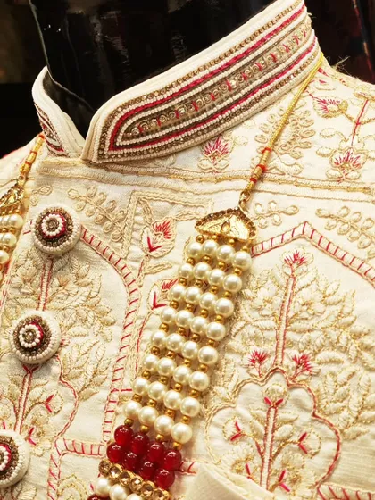 The beauty is in the details. This close-up showcases the exquisite hand embroidery, combining threadwork, beads, and stones on the collar of a custom off-white sherwani, reflecting true craftsmanship.