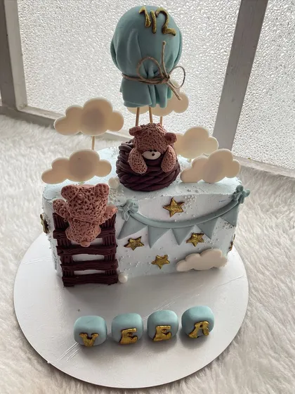 A "teddy bear in a hot air balloon" half-cake. The soft blue and brown colors are perfect for a baby boy's celebration.
