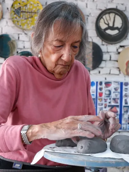 A student carefully works on small, eye-like sculptures, preparing them for the Raku firing. Even small pieces can have a big impact with this technique.