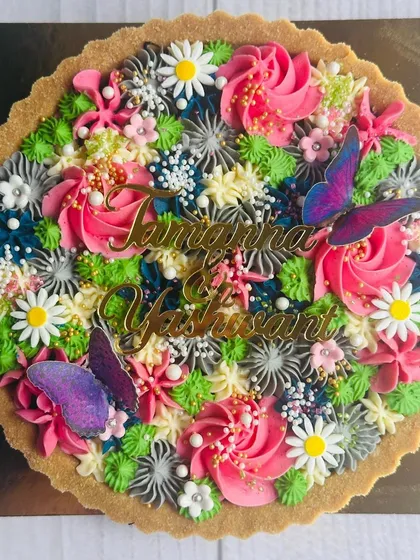 I love creating desserts for special beginnings, like this bespoke tart for a wedding ritual. It features the couple's names and is decorated with a garden of colorful buttercream flowers and butterflies to celebrate their journey.