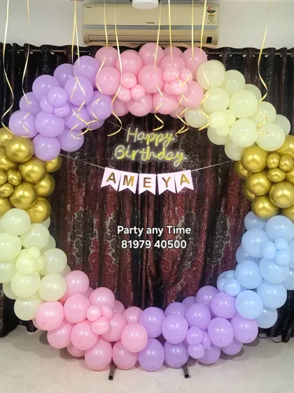 A pastel rainbow circular balloon arch for a home birthday party.