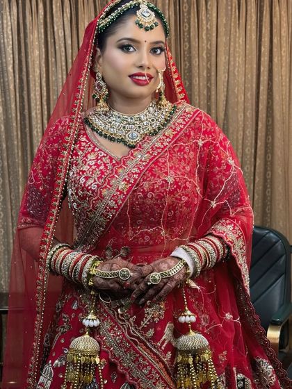 A full-length view of a stunning bride in her red lehenga. The complete look, from the makeup to the jewelry and outfit, comes together to create a picture of bridal perfection.