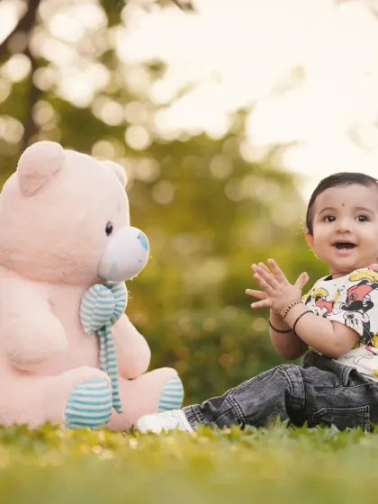 Clapping with joy, this toddler shares a happy moment with his teddy bear friend on the grass. These are the candid, heartwarming shots I love to capture.