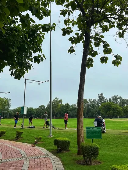 The brick path winds alongside the lush driving range, where golfers are busy with their weekend practice.